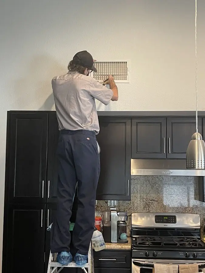 Technician inspecting an air vent during HVAC service in South Miami Heights